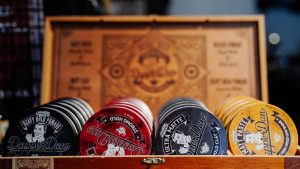 Close-up of various vintage-style hair products in a wooden box with decorative design.