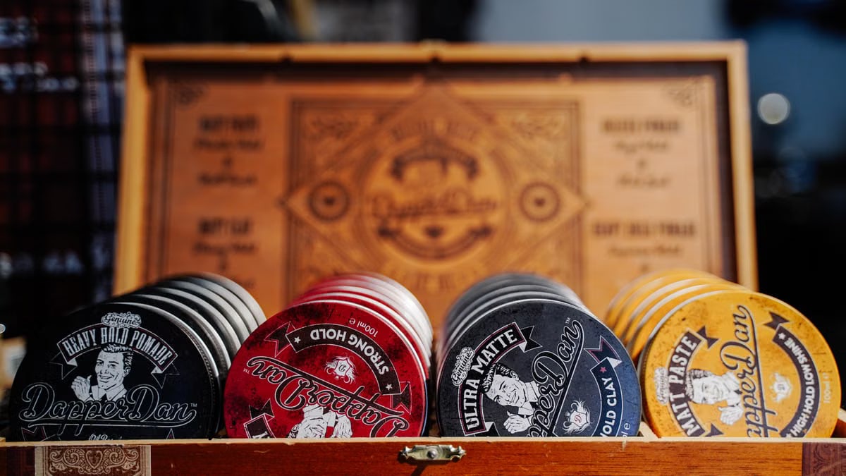 Close-up of various vintage-style hair products in a wooden box with decorative design.